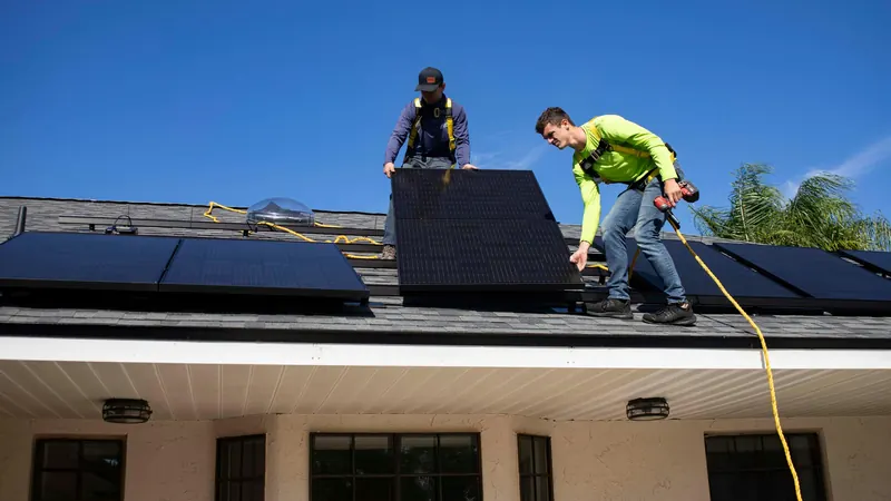 Dos instaladores colocando un panel solar sobre una cubierta