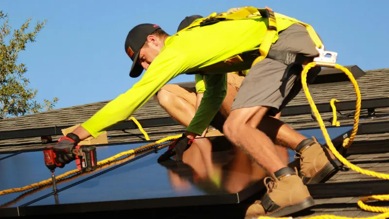 Instalador atornillando una placa solar sobre el tejado de una vivienda en Mieres
