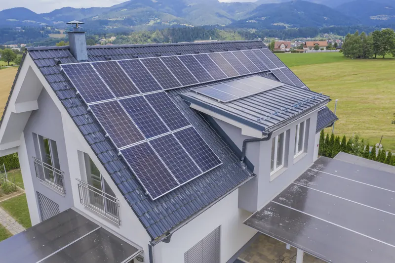 Tejado de vivienda con placas solares y prados verdes al fondo en Siero
